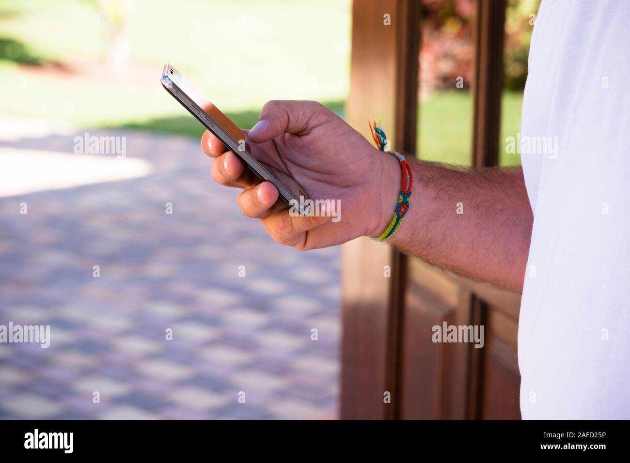 Close up of man hand using modern cellular phone outdoor - people and technology - caucasian adult messaging with black device Stock Photo