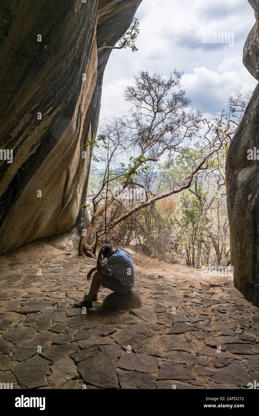 Matobo Hills national park, zimbabwe. A man rests after a climb to the Nswatugi Cave, which is filled with prehistoric rock paintings. Stock Photo