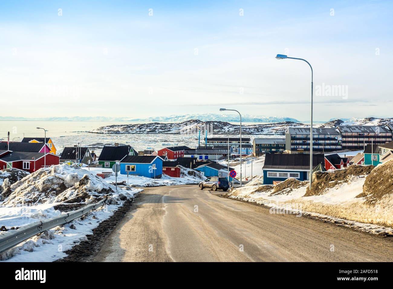 Arctic city center panorama with colorful Inuit houses on the rocky hills covered in snow with snow and mountain in the background, Ilulissat, Avannaa Stock Photo