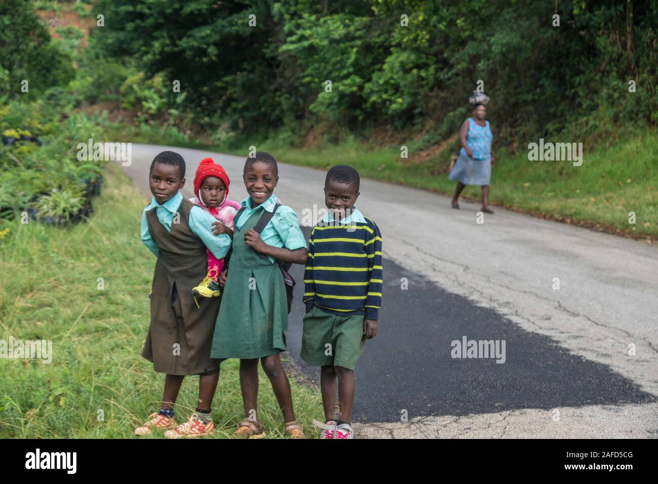 Zimbabwe, A rural area in the eastern highlands. A young girl, with a short haircut to aid in preventing louses, carries her young sister on her back Stock Photo