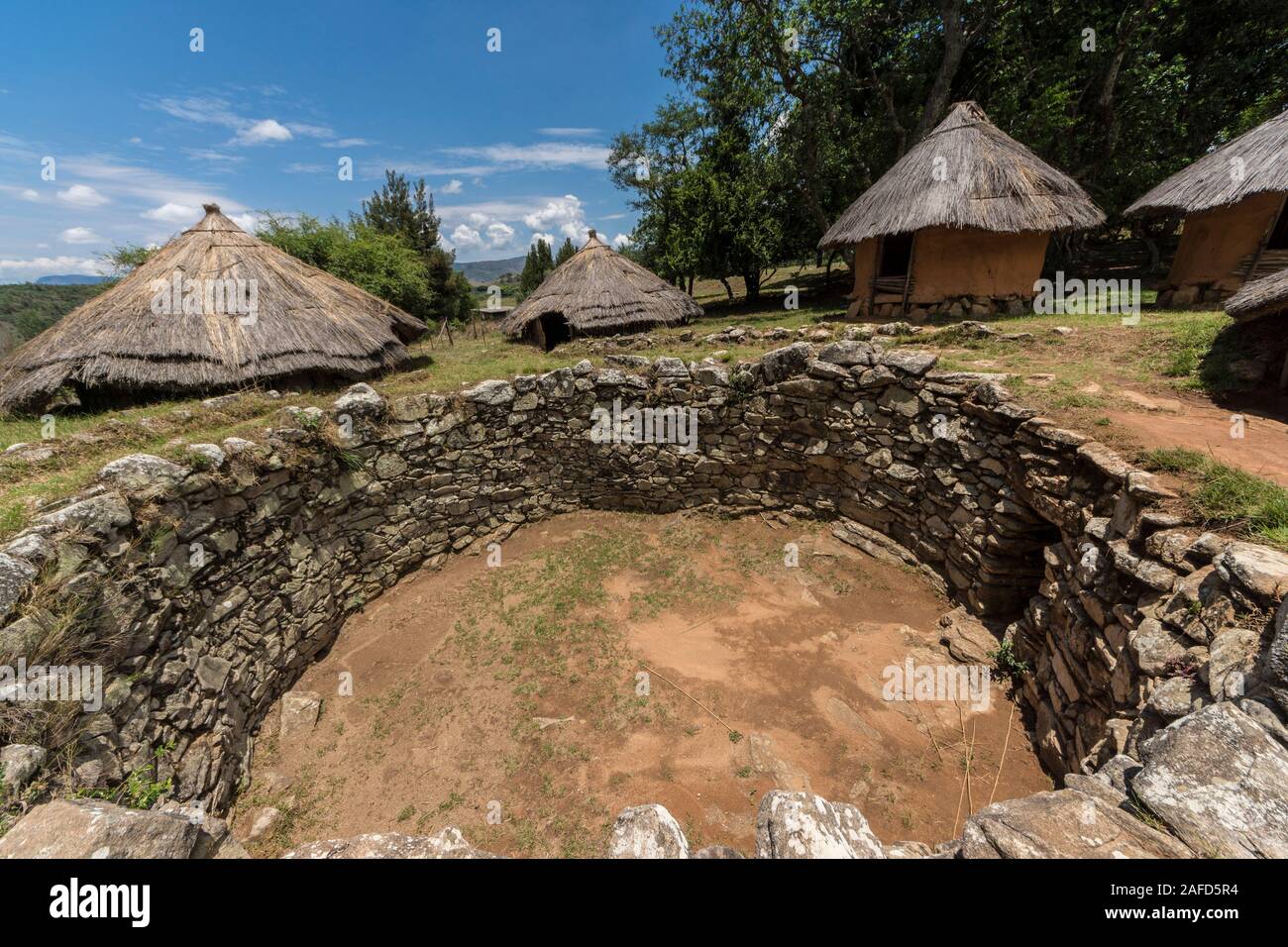 Nyanga National Park, Zinmbabwe. ancient pits - probably for cattle - with a recreation of a Kraal (traditional village) in the background. Stock Photo