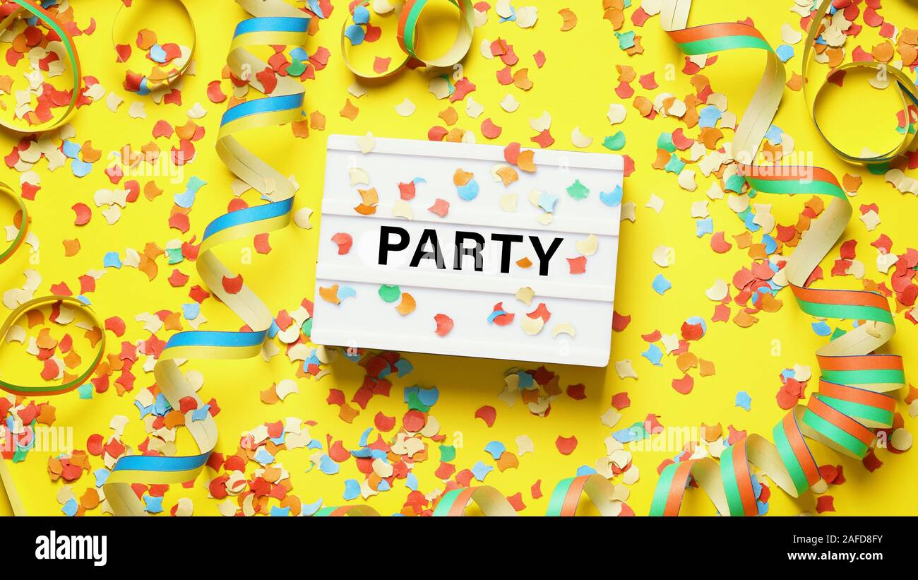party celebration flat lay with confetti streamers and text on lightbox Stock Photo