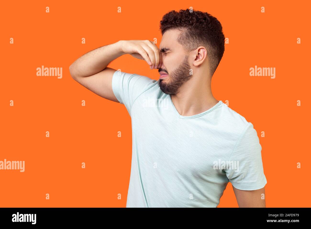 Stinky smell. Side view of confused brunette man with beard in white t-shirt  holding breath with fingers on nose, disgusted by bad odor fart, gesturin  Stock Photo - Alamy