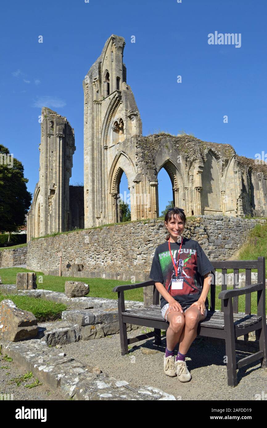 Woman in her early 40s on a bench at Glastonbury Abbey, Glastonbury, Somerset, UK. The legendary burial place of King Arthur. Stock Photo