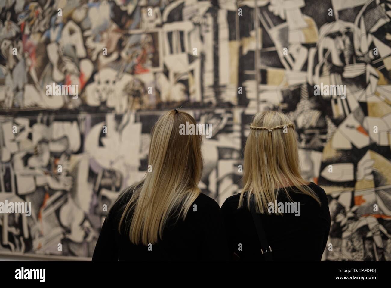 TWO YOUNG BLONDE WOMEN LOOKING AT A PAINTING OF DIA AL AZZAWI IN TATE MODERN GALLERY LONDON - SABRA AND SHATILA MASSACRE 1982-1983 PAINTING - LONDON MUSEUM - TATE MODERN - LONDON ART © Frédéric BEAUMONT Stock Photo