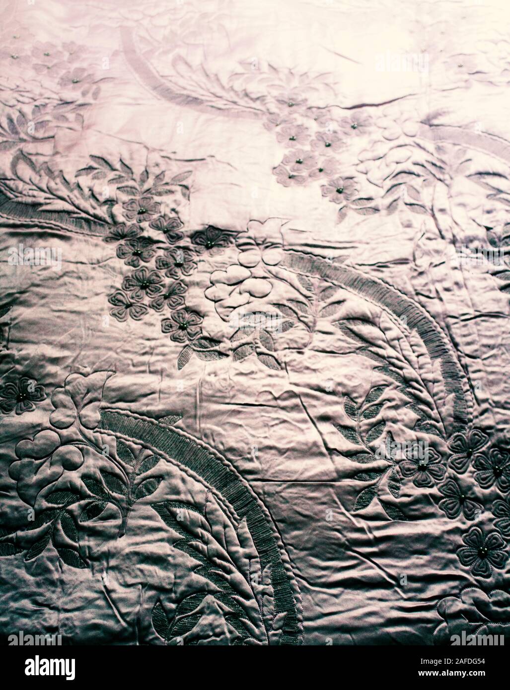 Hand quilting is still popular. Close up image of a quilt with petal leaves and pearls, from