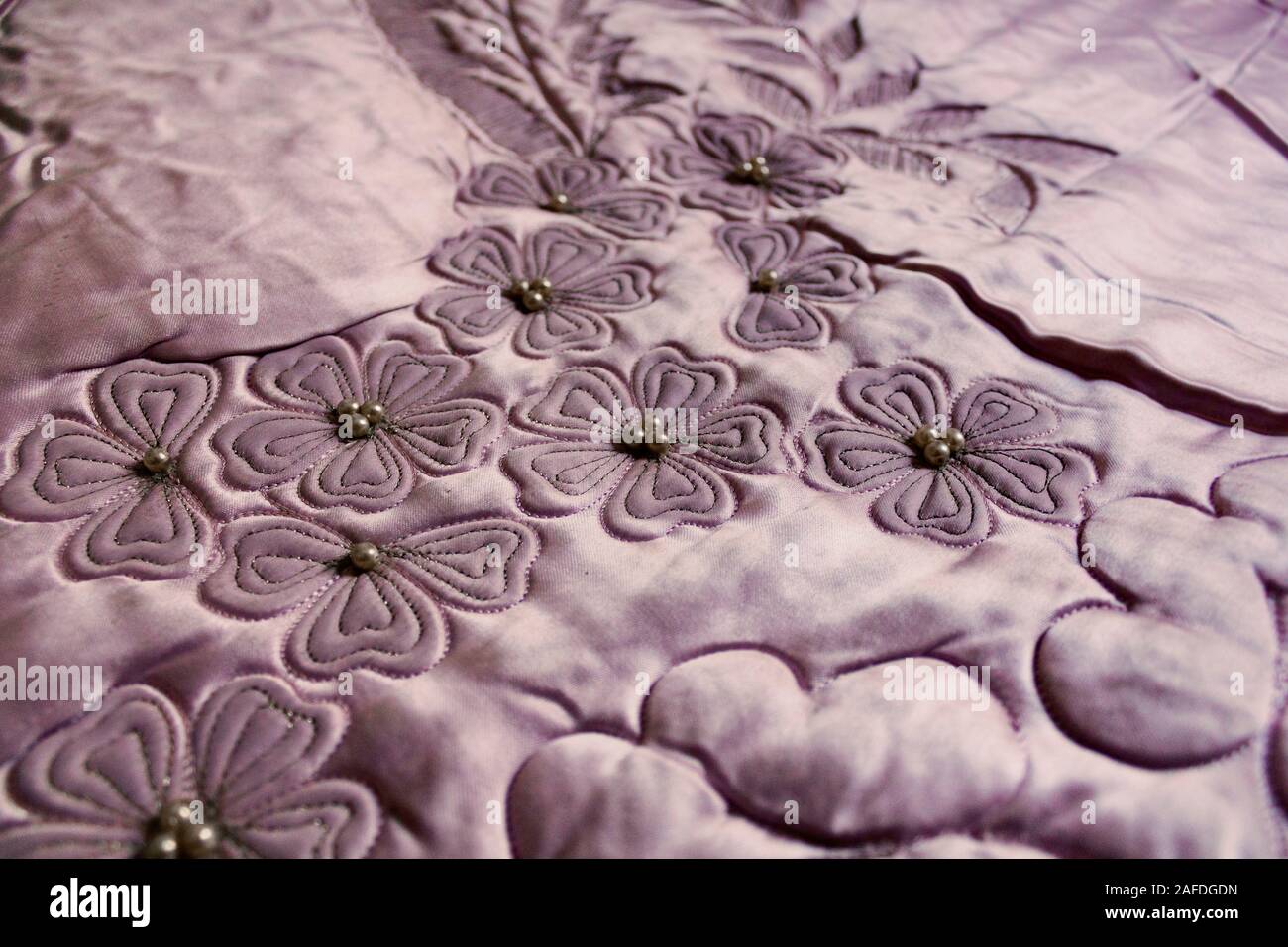 Hand quilting is still popular. Close up image of a quilt with petal leaves and pearls, from 1950s. Stock Photo