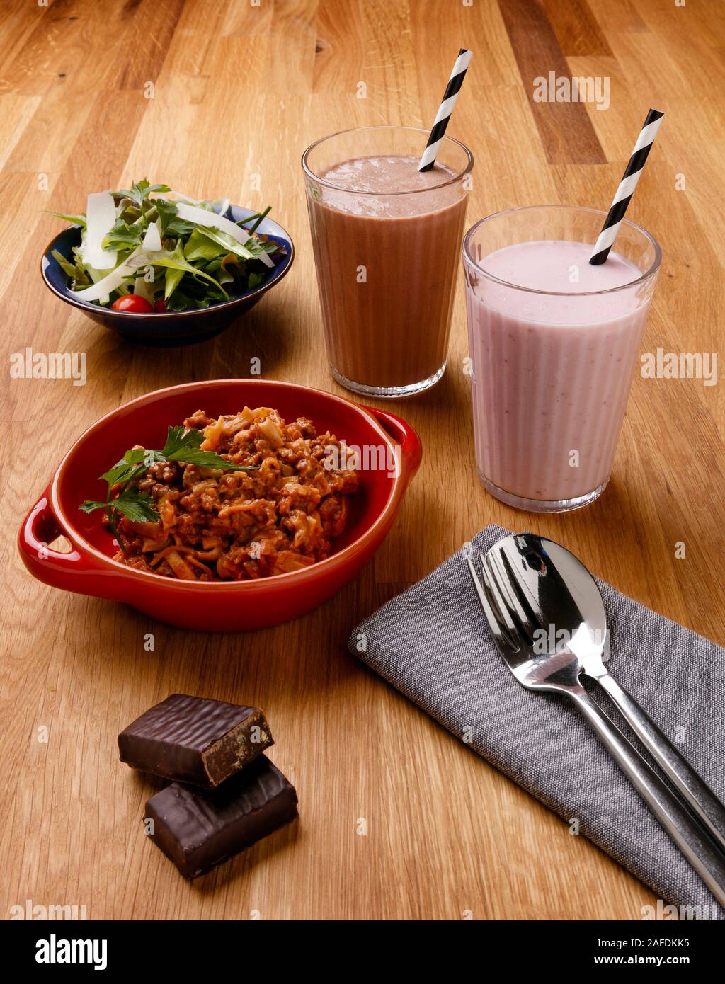 Calorie controlled daily meal plan, including breakfast milkshake, a snack and evening meal, shot on a wooden background Stock Photo