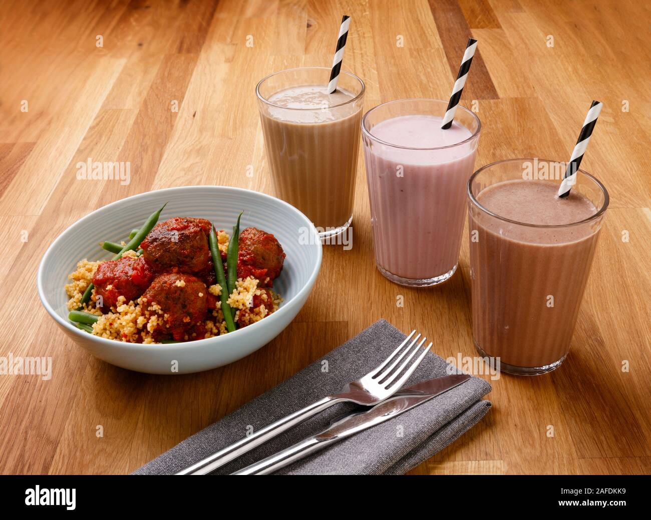 Calorie controlled daily meal plan, including breakfast milkshake, a snack and evening meal of delicious meat balls, shot on a wooden background Stock Photo
