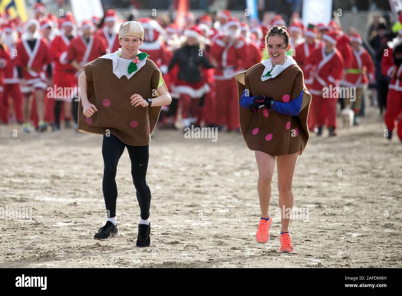 People dressed as Christmas puddings get a head start before the annual Chase the Pudding race, where competitors chase after a runner dressed as a Christmas pudding as they run a 5km route along Weymouth beach front. Stock Photo