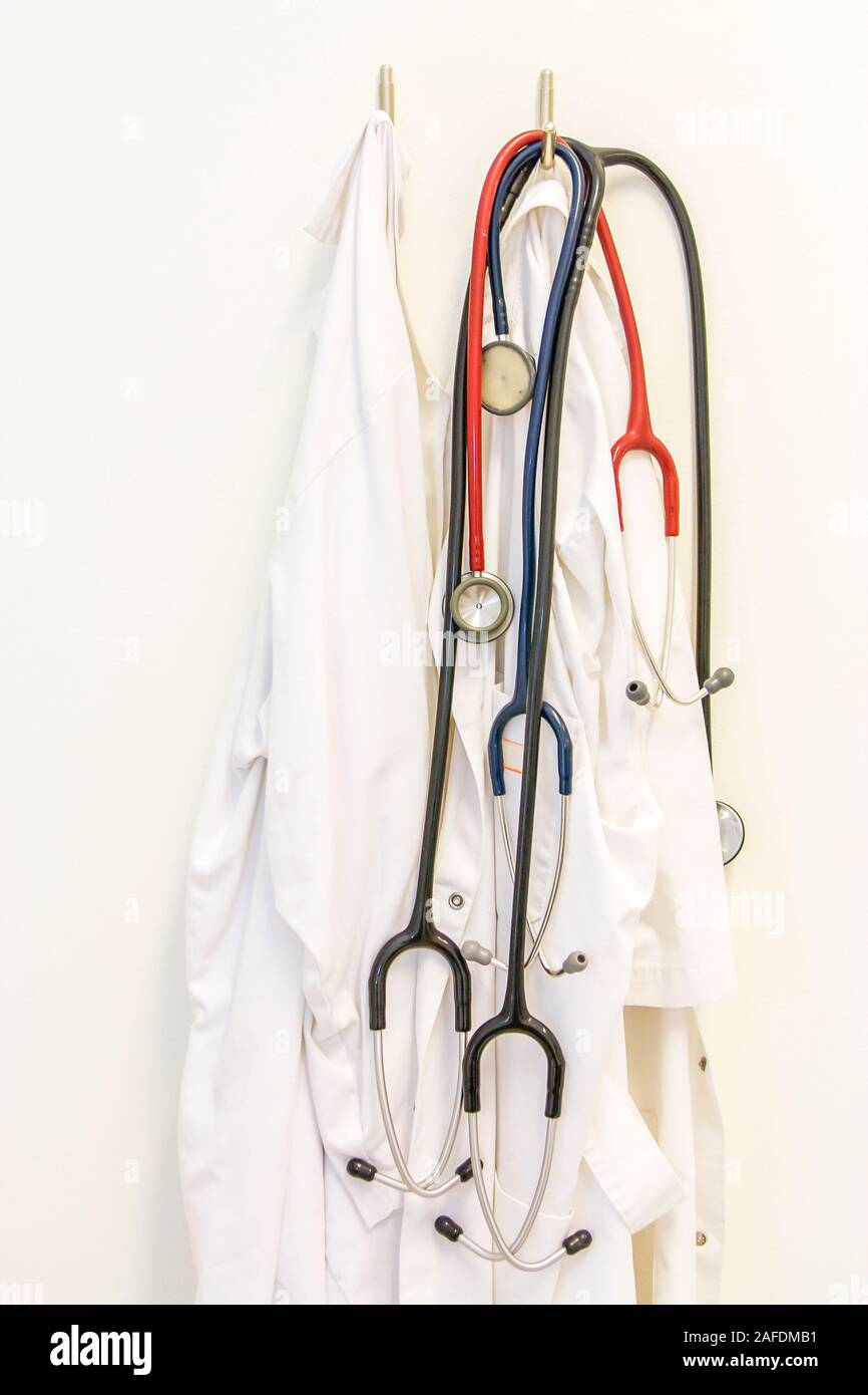 a couple of white doctors coats and stethoscopes hanging on the wall
