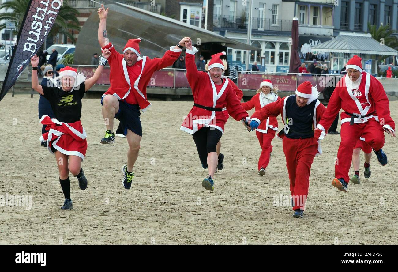 Weymouth, Dorset, UK. 15th Dec, 2019. Two Christmas puddings were the focus for over 200 runners dressed in santa outfits in Weymouth Dorset as they tried to catch the fleet of foot couple along a 5Km course over the town's beach. This annual event brings runners from all over the South of England to the wintery coast for a fun morning event that raises money for charity. This year a male and female pud! And if the runners do not catch the puddings they do each receive one as they cross the finishing line. Picture : Geoff Moore Credit: Dorset Media Service/Alamy Live News Stock Photo