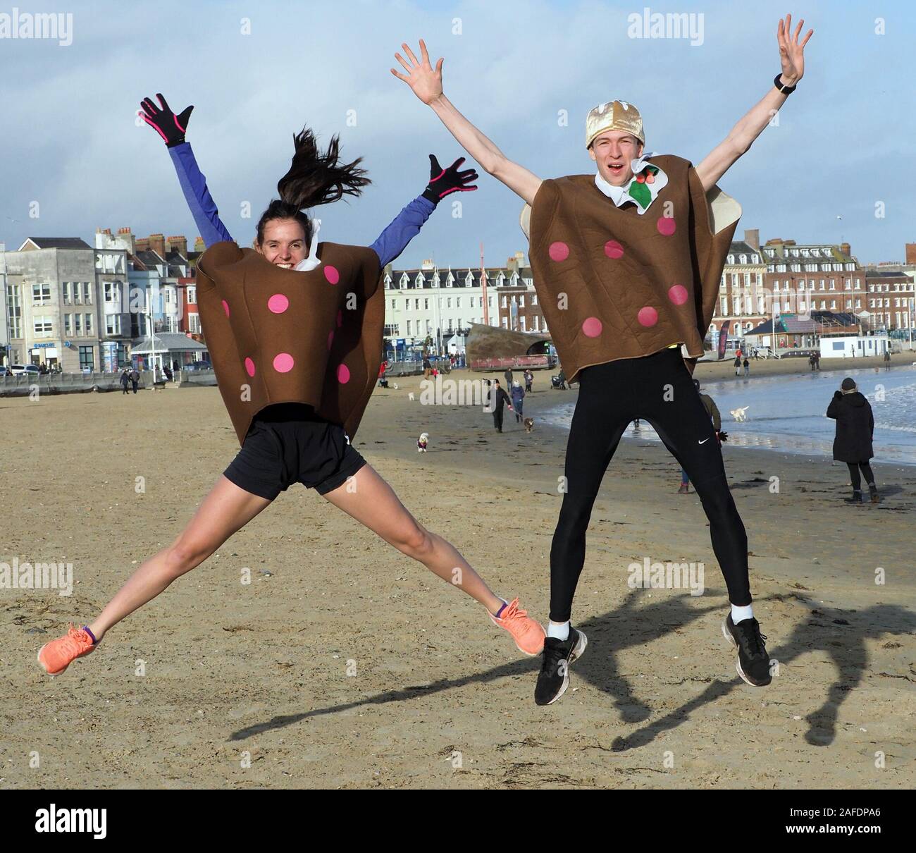 Weymouth, Dorset, UK. 15th Dec, 2019. Two Christmas puddings, Charlie Scott, left and Andrew Dumbrell, were the focus for over 200 runners dressed in santa outfits in Weymouth Dorset as they tried to catch the fleet of foot couple along a 5Km course over the town's beach. This annual event brings runners from all over the South of England to the wintery coast for a fun morning event that raises money for charity. This year a male and female pud! And if the runners do not catch the puddings they do each receive one as they cross the finishing line. Picture : Geoff Moore Stock Photo