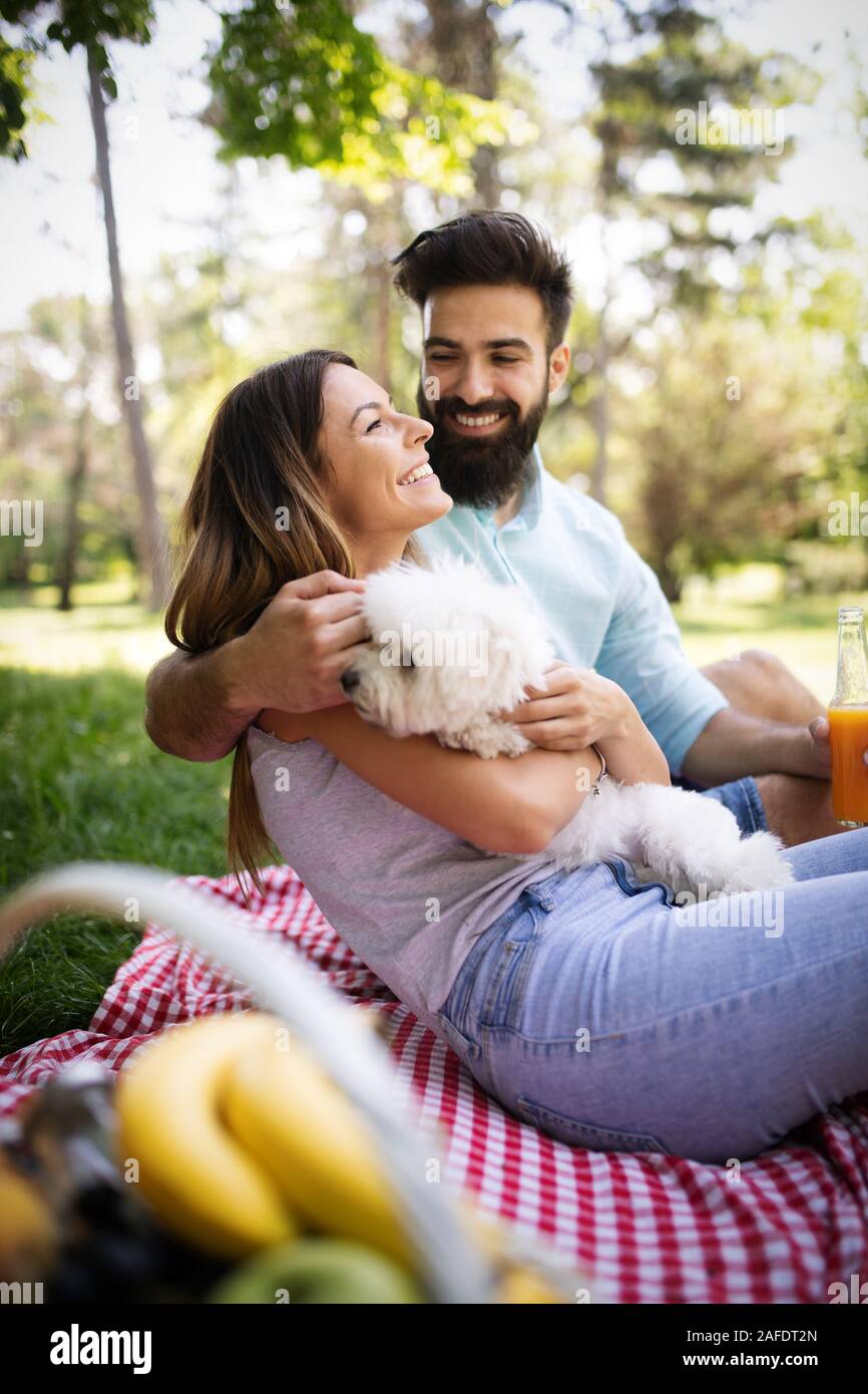 Lifestyle, happy couple resting at a picnic in the park with a dog Stock Photo