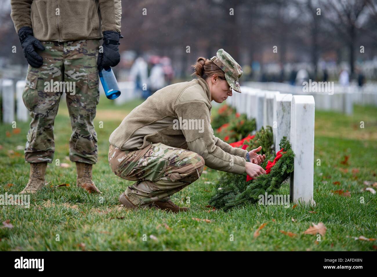 Arlington, United States of America. 14 December, 2019. A U.S. soldier places a wreath on the gravesite of a fallen service member during the 28th Wreaths Across America Day at Arlington National Cemetery December 14, 2019 in Arlington, Virginia. More than 38,000 volunteers place wreaths at every gravesite at Arlington National Cemetery and other sites around the nation.  Credit: Elizabeth Fraser/DOD/Alamy Live News Stock Photo