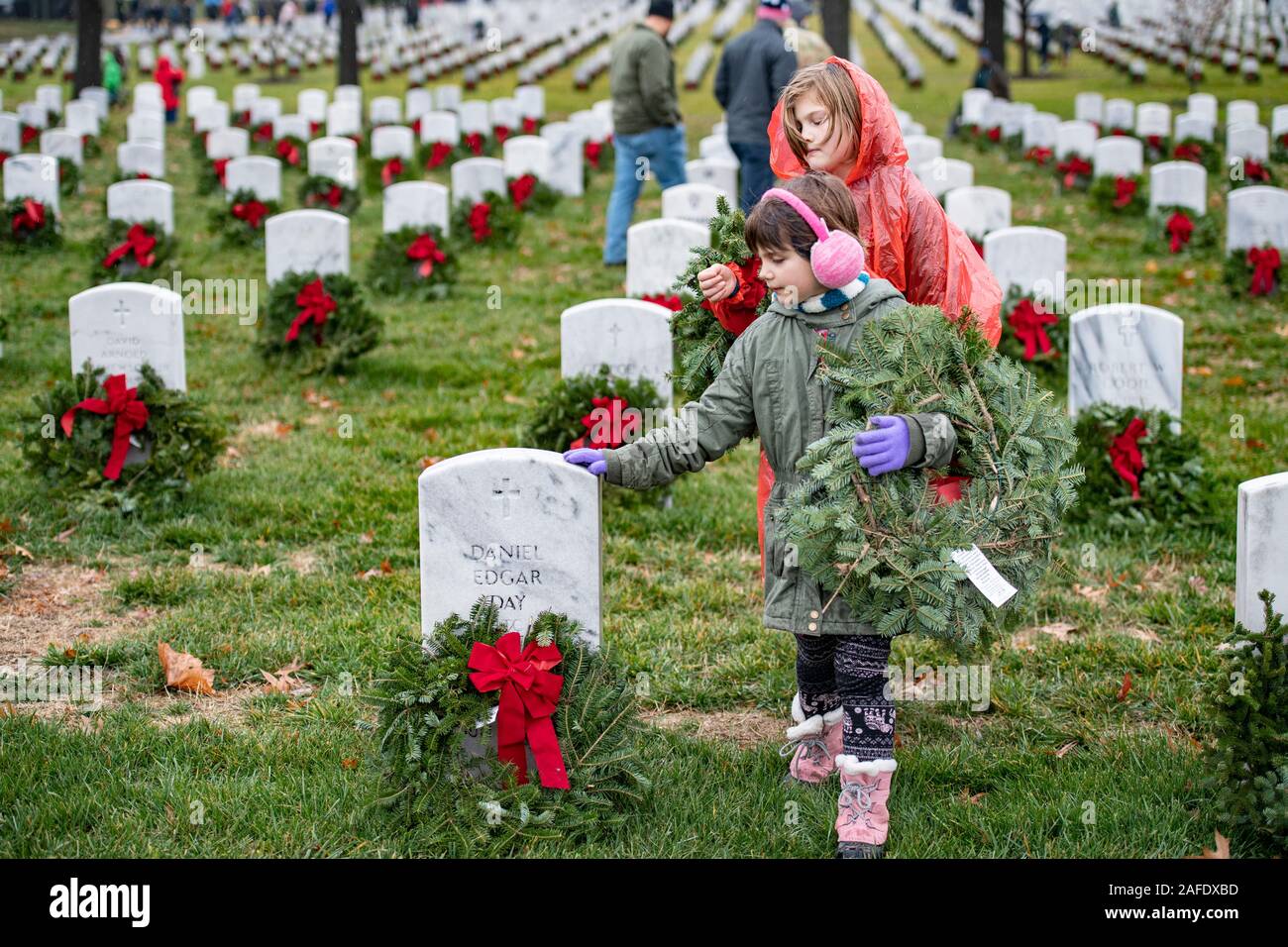 Arlington, United States of America. 14 December, 2019. A young girl touches a grave marker as she places a wreath on the gravesite of a fallen service member during the 28th Wreaths Across America Day at Arlington National Cemetery December 14, 2019 in Arlington, Virginia. More than 38,000 volunteers place wreaths at every gravesite at Arlington National Cemetery and other sites around the nation.  Credit: Elizabeth Fraser/DOD/Alamy Live News Stock Photo