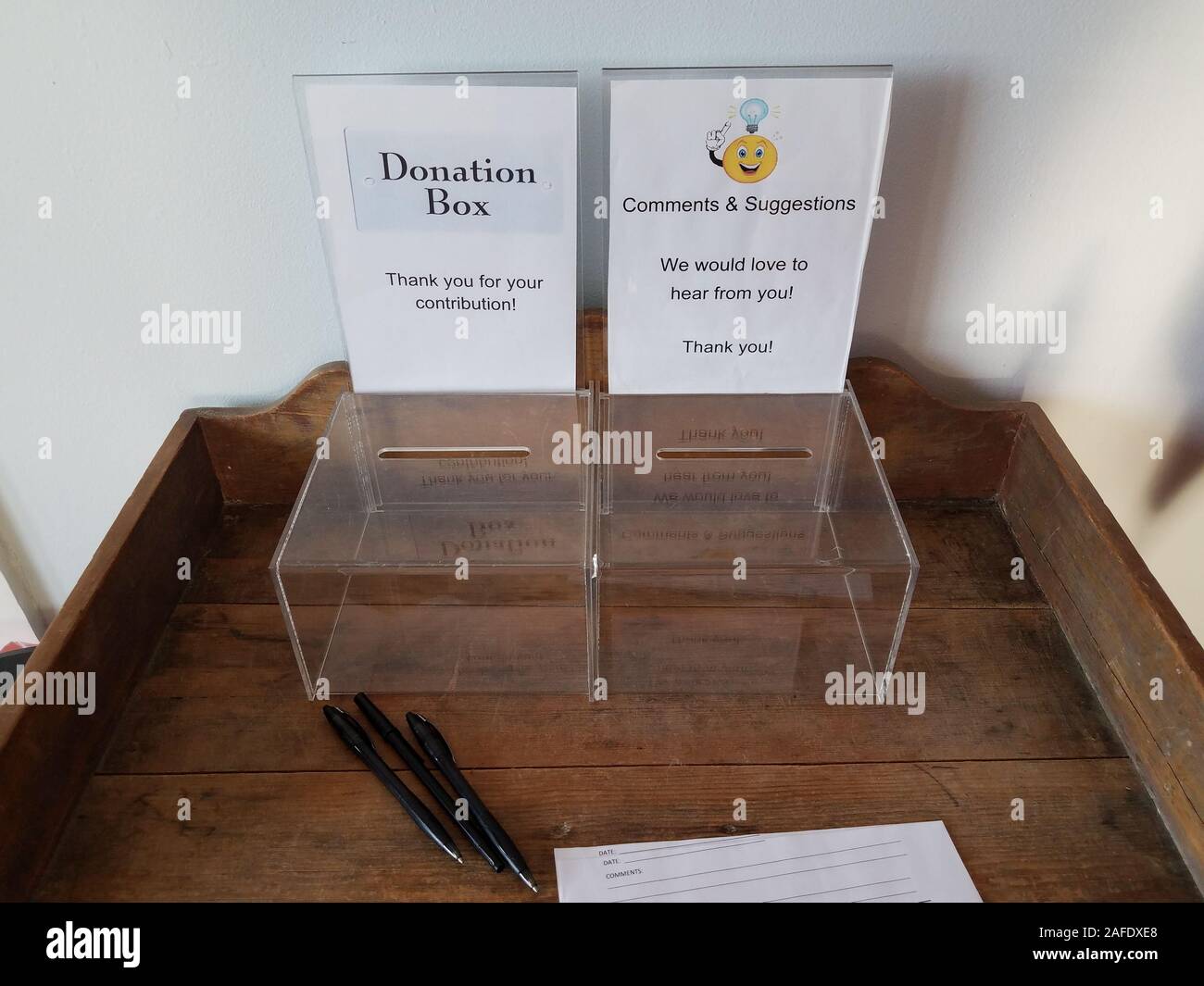 plastic donation and comment or suggestion box with pen and paper on