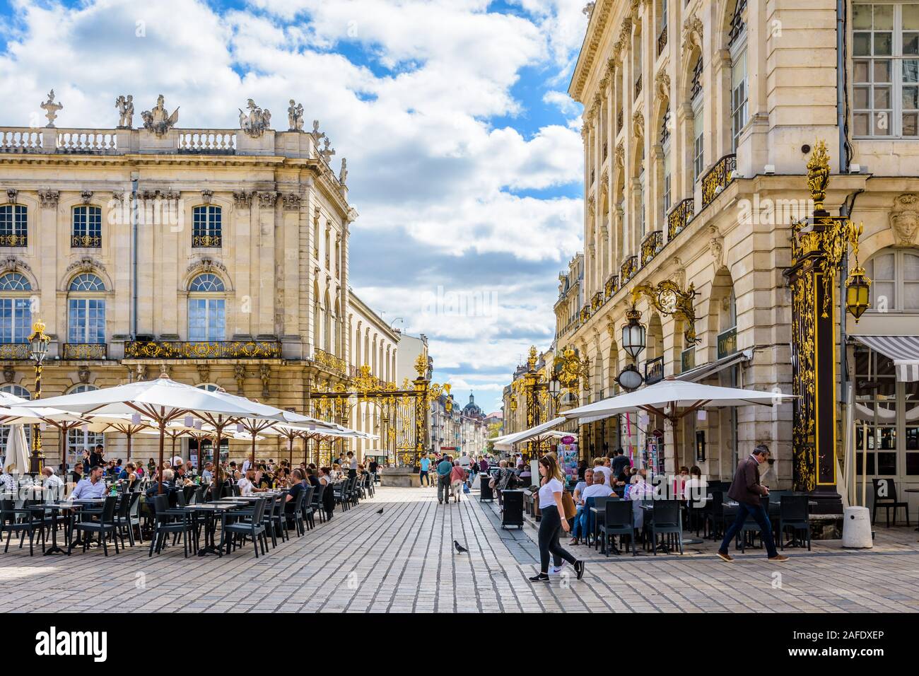 Terraces of sidewalk cafes at the foot of the city hall and the pavillon Jacquet on the Stanislas square in Nancy, France, closed by a gilded gate. Stock Photo