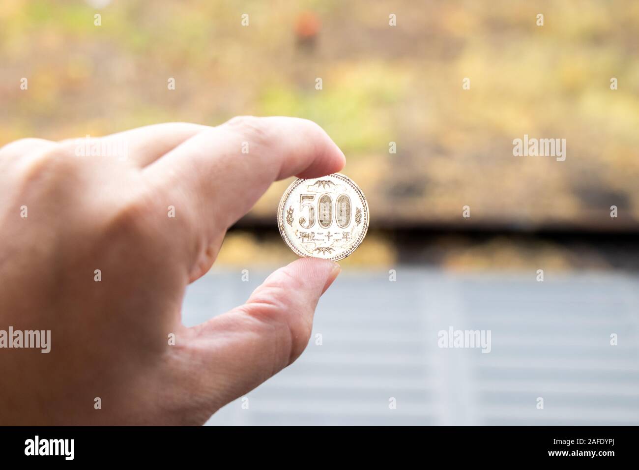 Man hold japanese coin 500 yen on blurred background Stock Photo