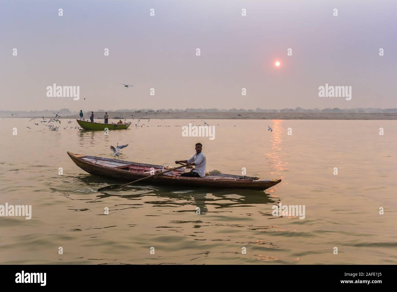 Young man in a row boat on the Ganges river in Varanasi, India Stock Photo