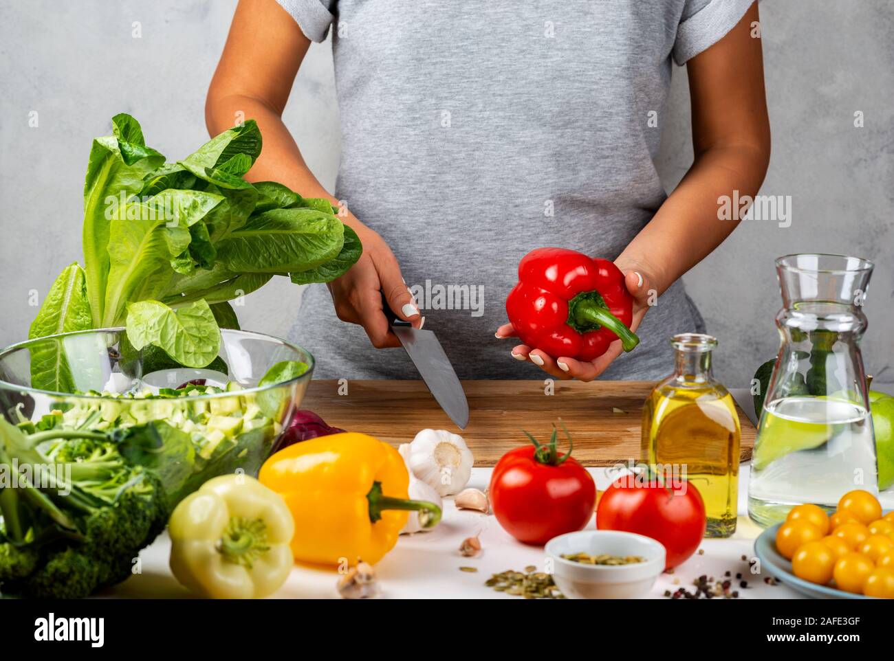 Red pepper and a knife in female hands. Woman is cooking salad. Healthy diet concept. Stock Photo