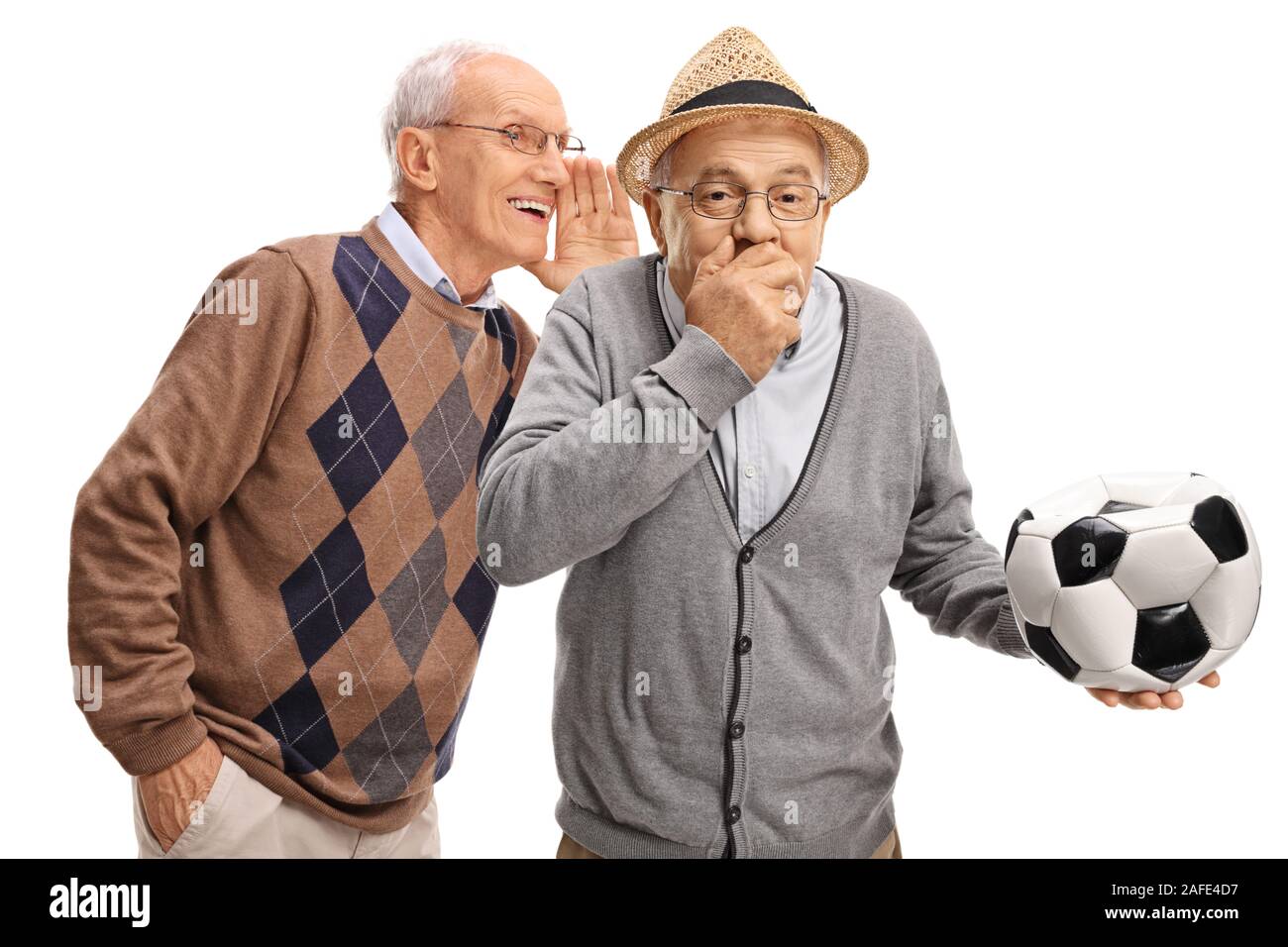Senior man whispering to friend holding a deflated soccer ball and laughing isolated on white background Stock Photo