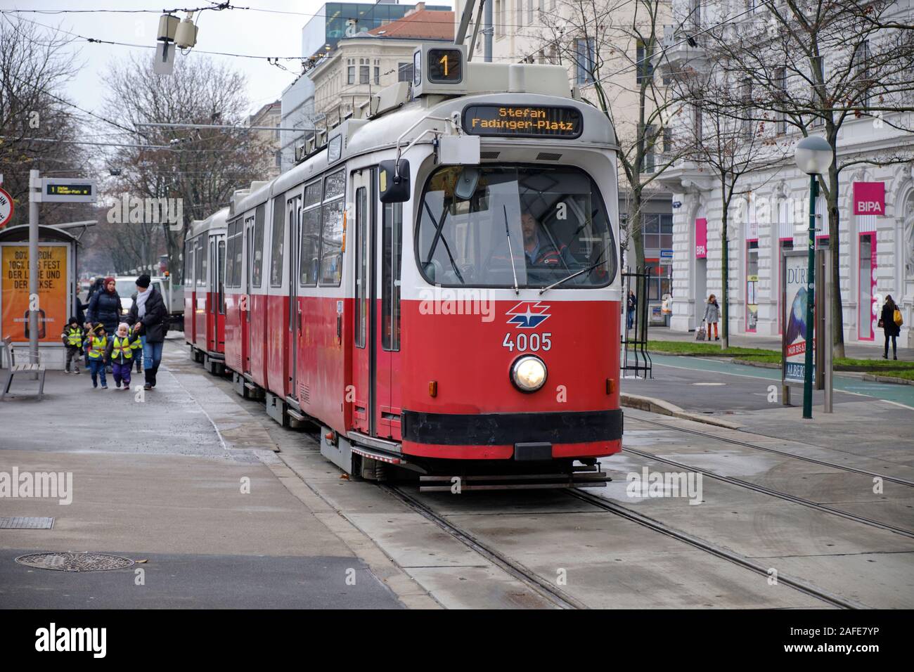 E2 type Vienna Tram at stop with driver in on school group rushing to catch it Stock Photo