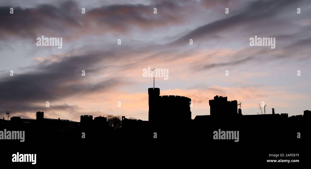 Windsor, Berkshire, UK. 15th December 2019. UK Weather: The iconic castle and the town's roof tops are silhouetted against vibrant sunrise colours at Windsor heralding a bright start following a night of heavy showers and high winds. Credit: Celia McMahon/Alamy Live News. Stock Photo