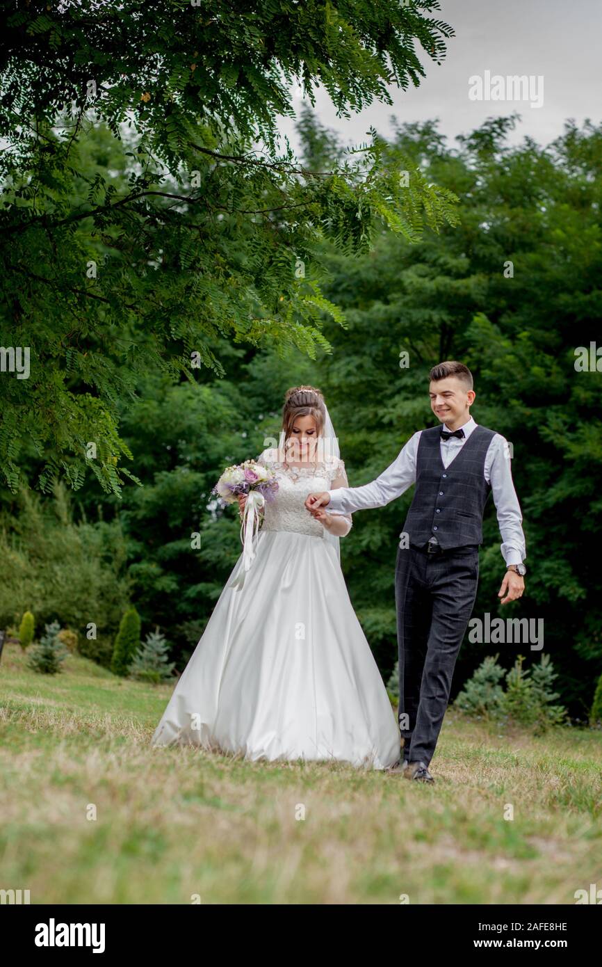 Happy bride and groom holding hands and walking in garden wedding day ...
