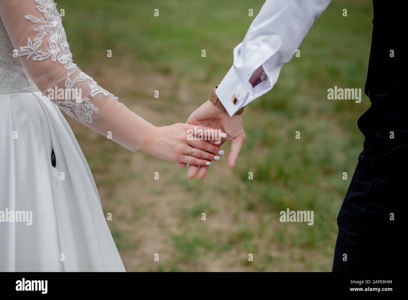 Happy bride and groom holding hands and walking in garden wedding day ...
