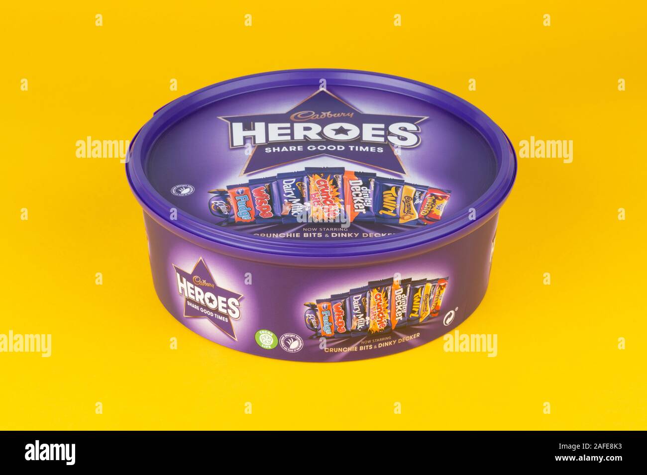A box of Cadburys Heroes chocolate confectionery shot on a yellow background. Stock Photo