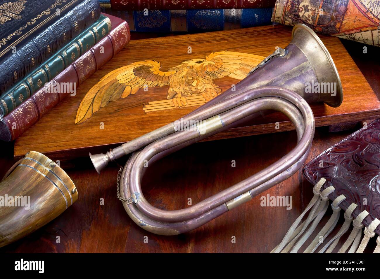 Old antique brass bugle with leather books and wooden eagle. Stock Photo