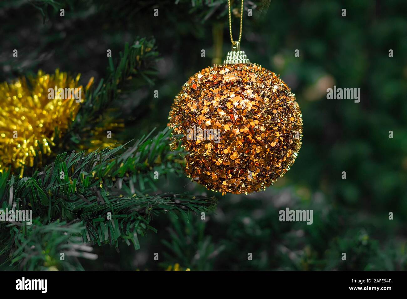 Decorative gold ball toy on Christmas tree. Approach of new year 2020. Front view is close. Stock Photo