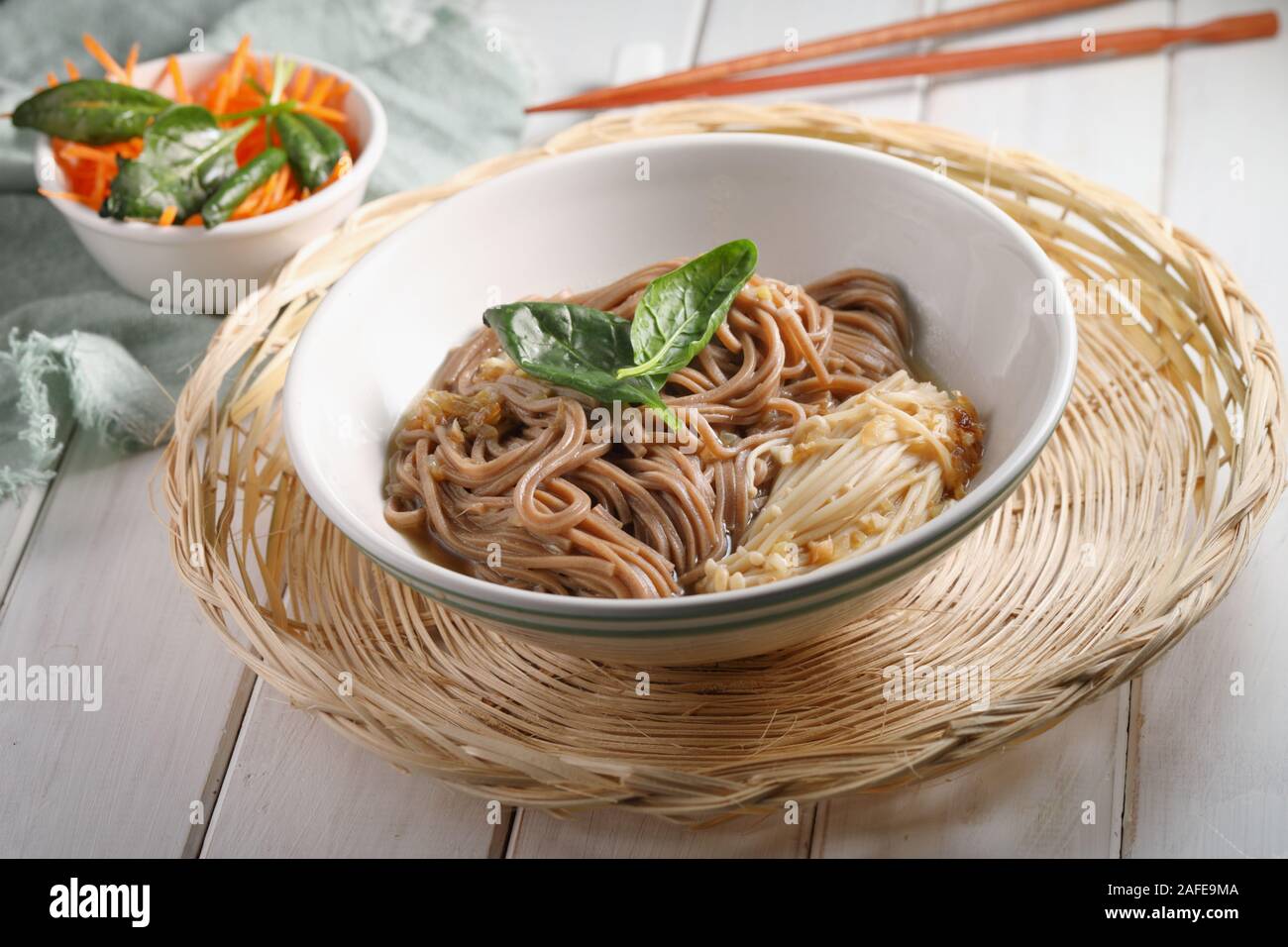 Japanese soup with Enoki mushrooms, soba noodles, spinach, carrot, and soy sauce Stock Photo