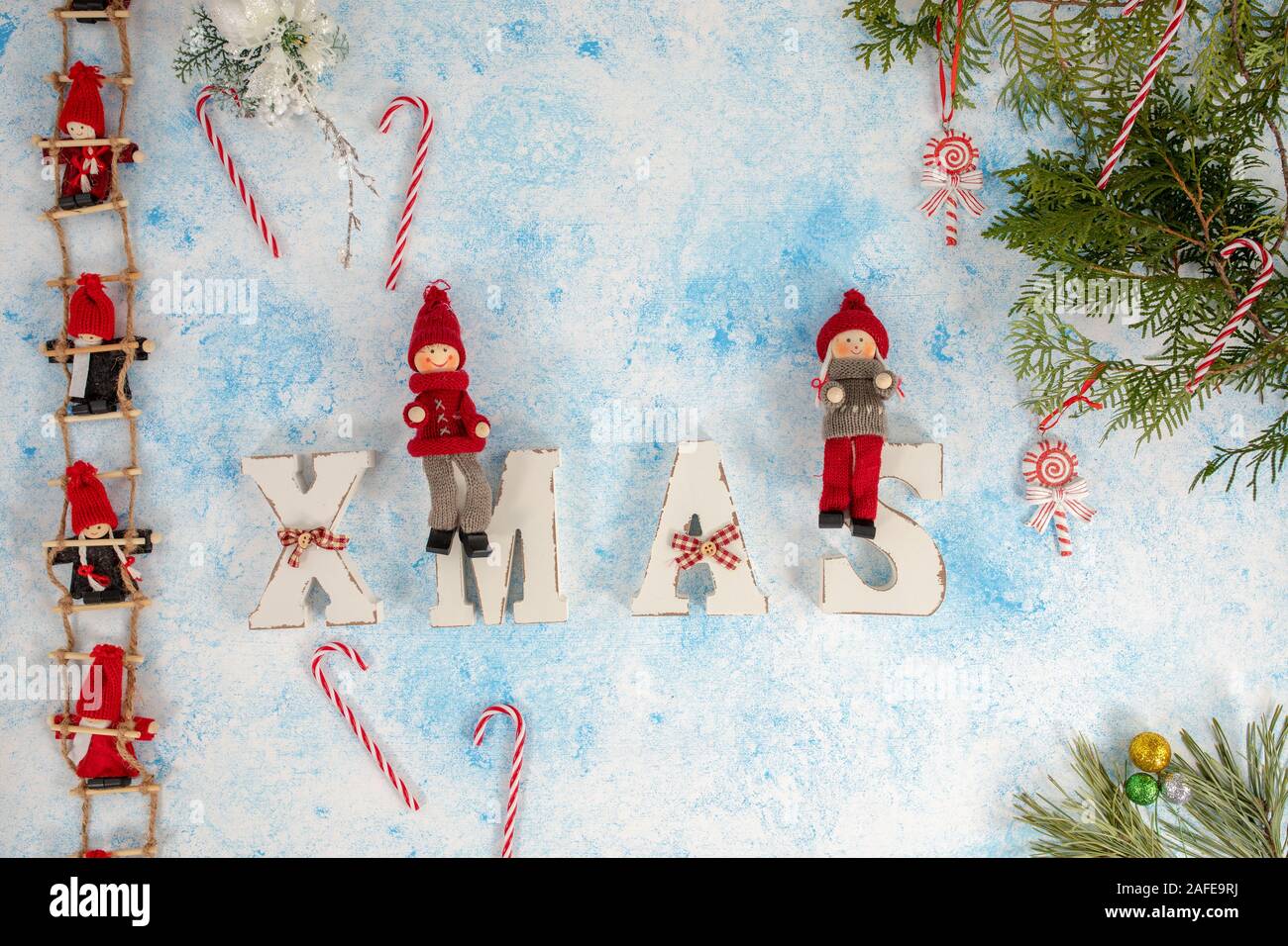 Little dwarf dolls are sitting on the Christmas stairs. Christmas decorations. wooden letters XMAS on a blue and white background Stock Photo
