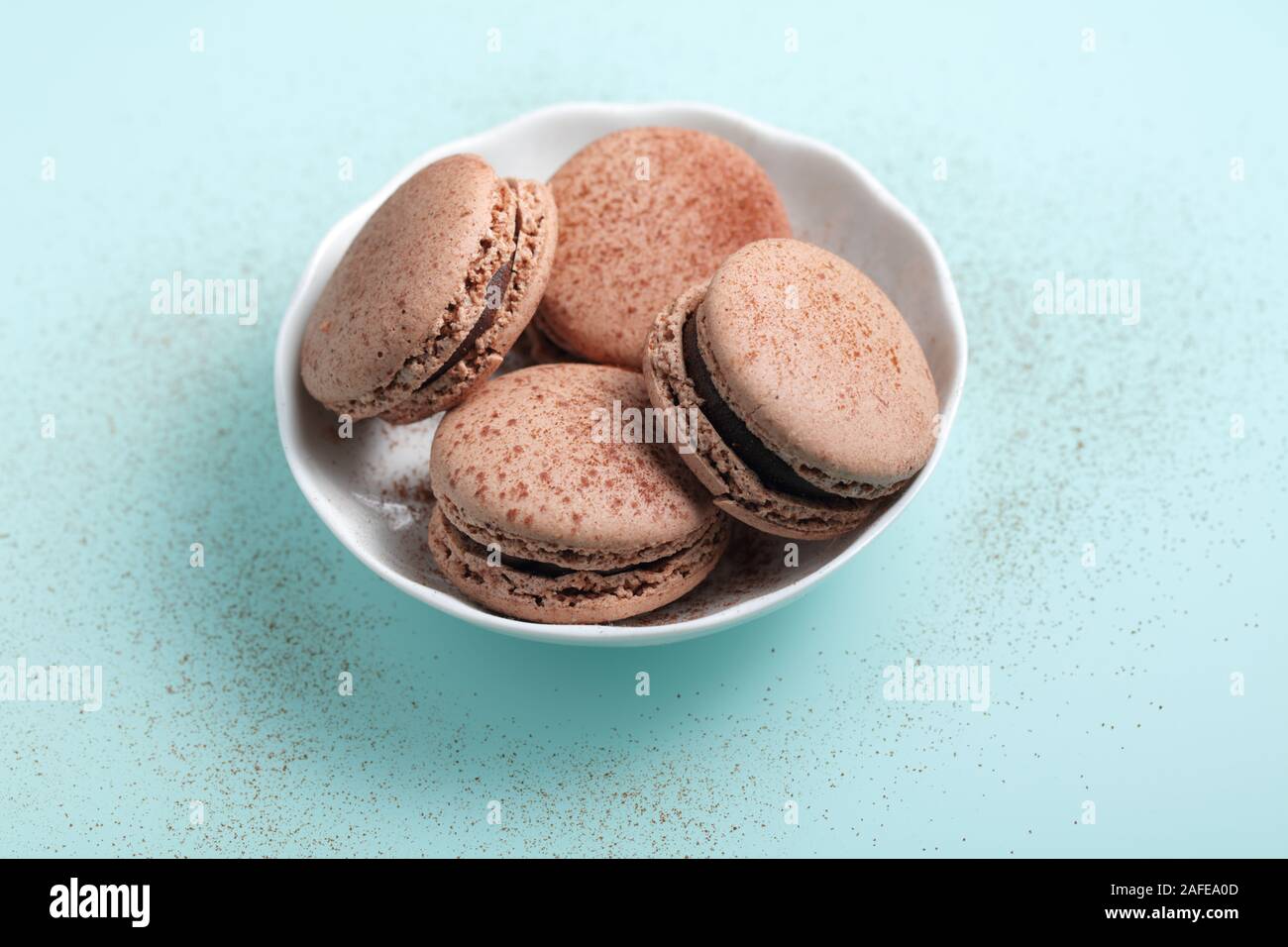 Four chocolate macarons confections against cyan background Stock Photo