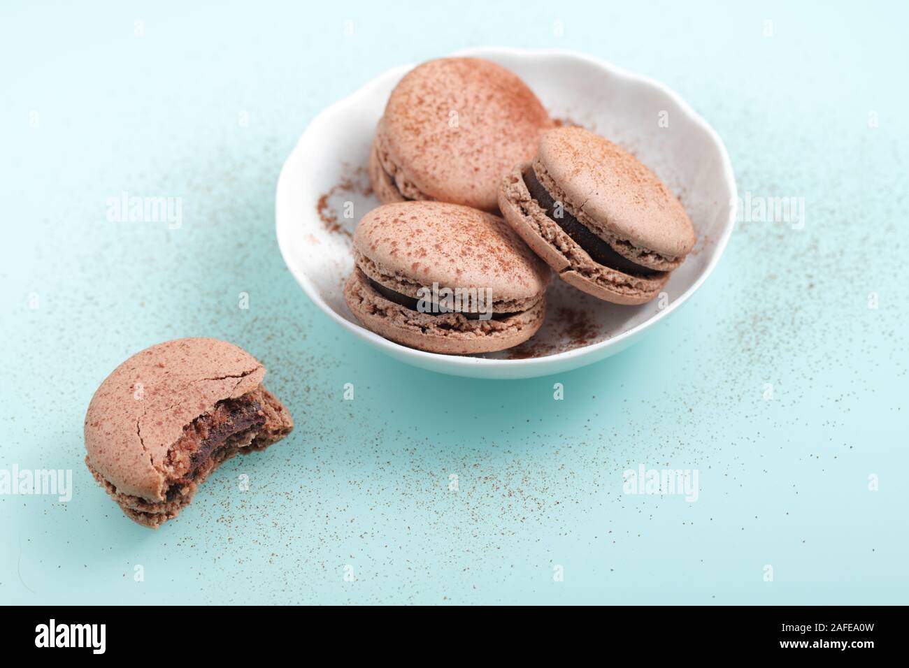 Chocolate macarons confections against cyan background Stock Photo