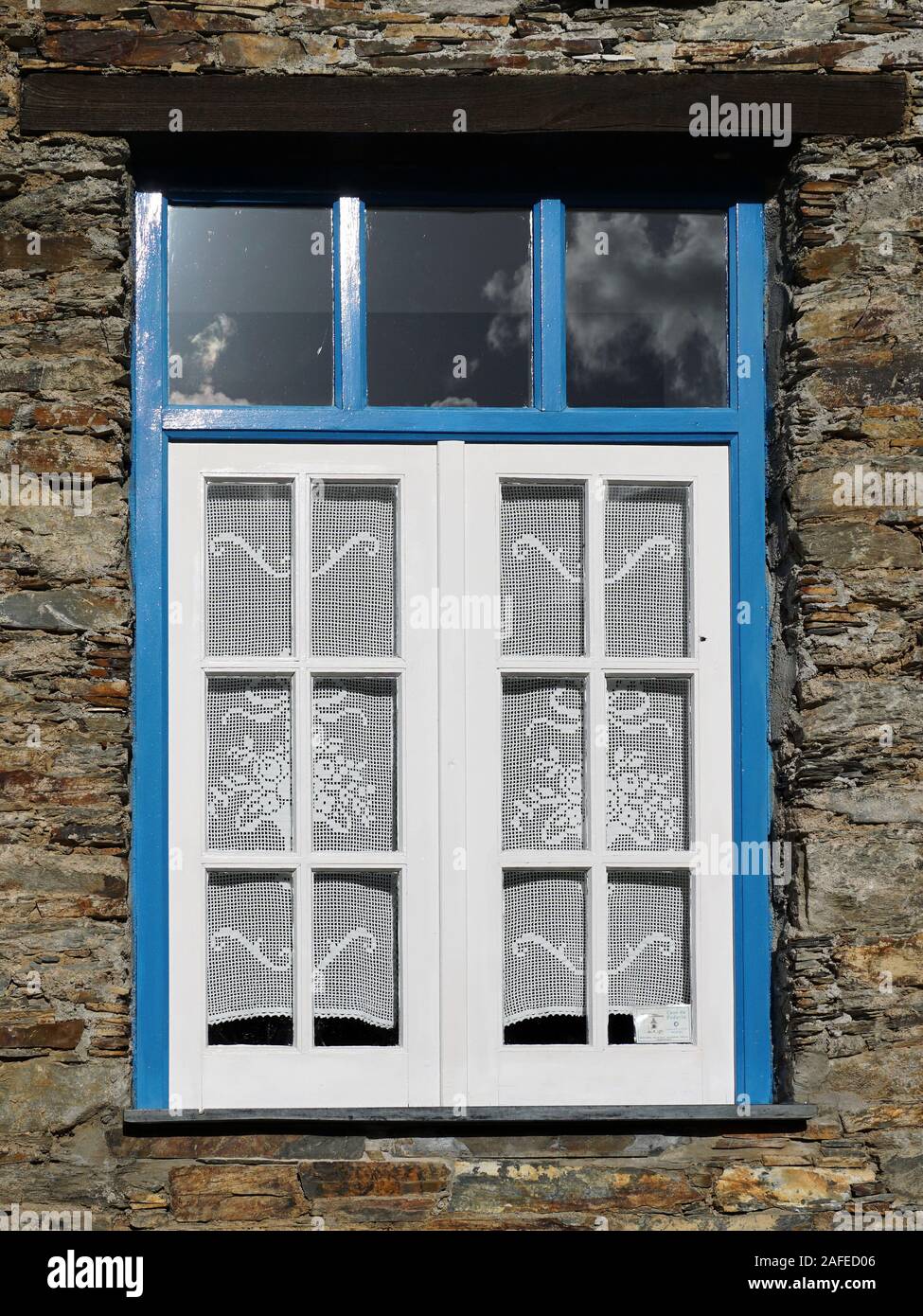 Old vintage blue window with blue trim and a rustic stone wall Stock Photo