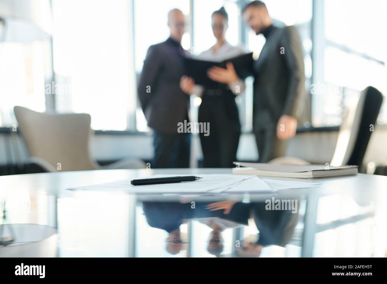 Pen on papers and notebook with business partners having negotiation Stock Photo