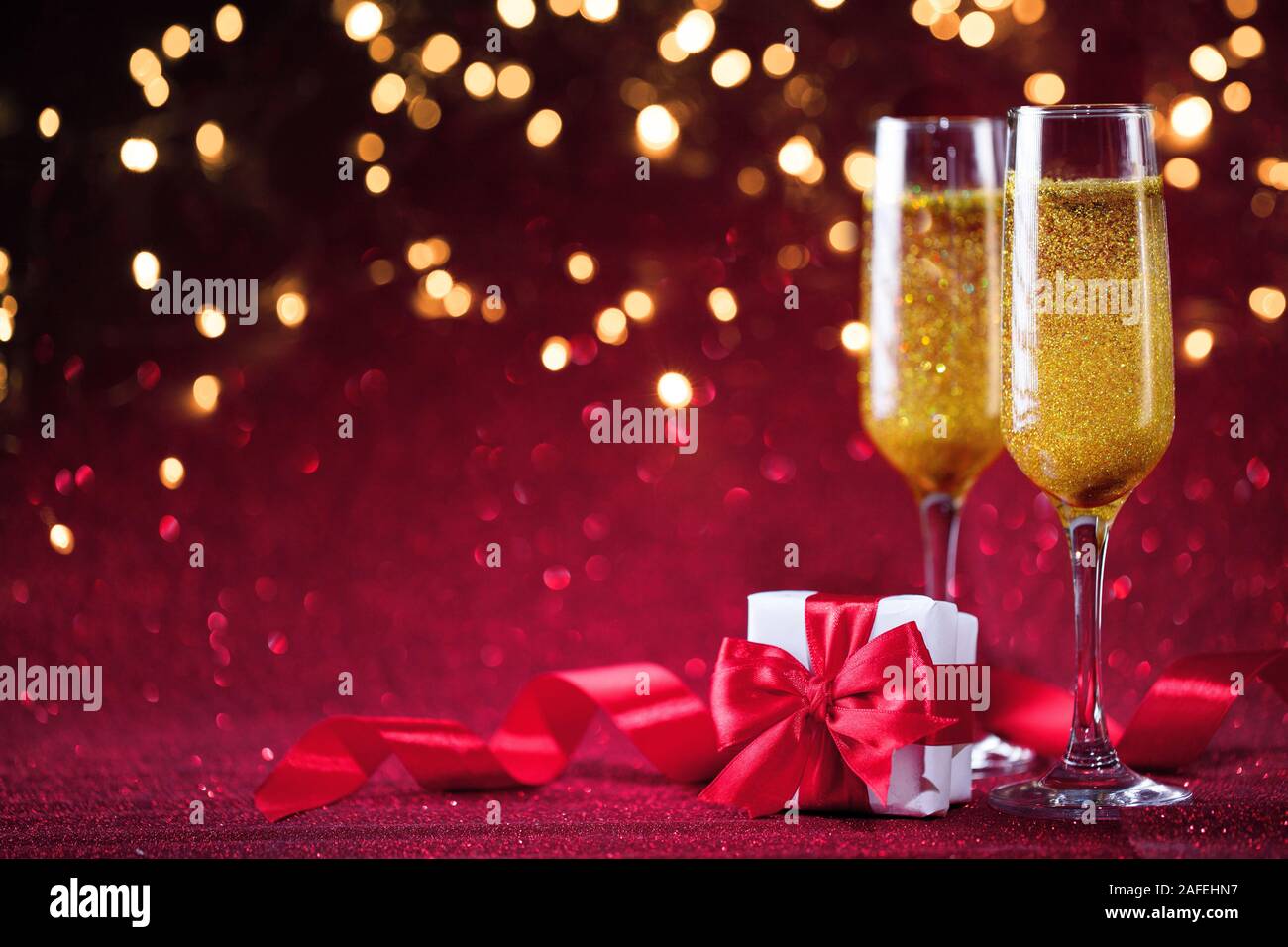 Champagne and gift box with red bow on red glitter background Stock ...