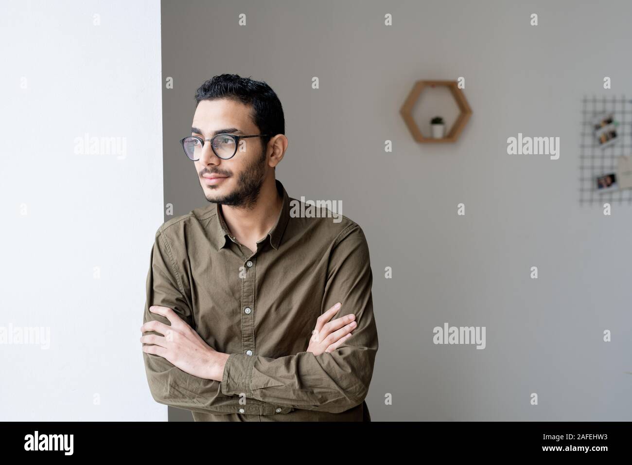 Young cross-armed businessman in eyeglasses and shirt looking through window Stock Photo