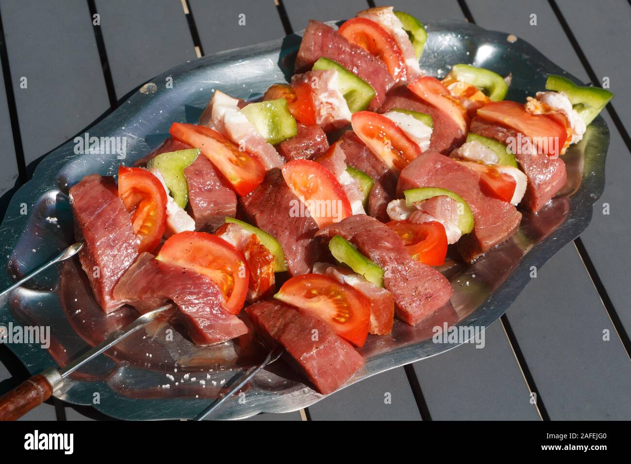 Beef, bacon, tomato and pepper brochettes on a pewter dish Stock Photo