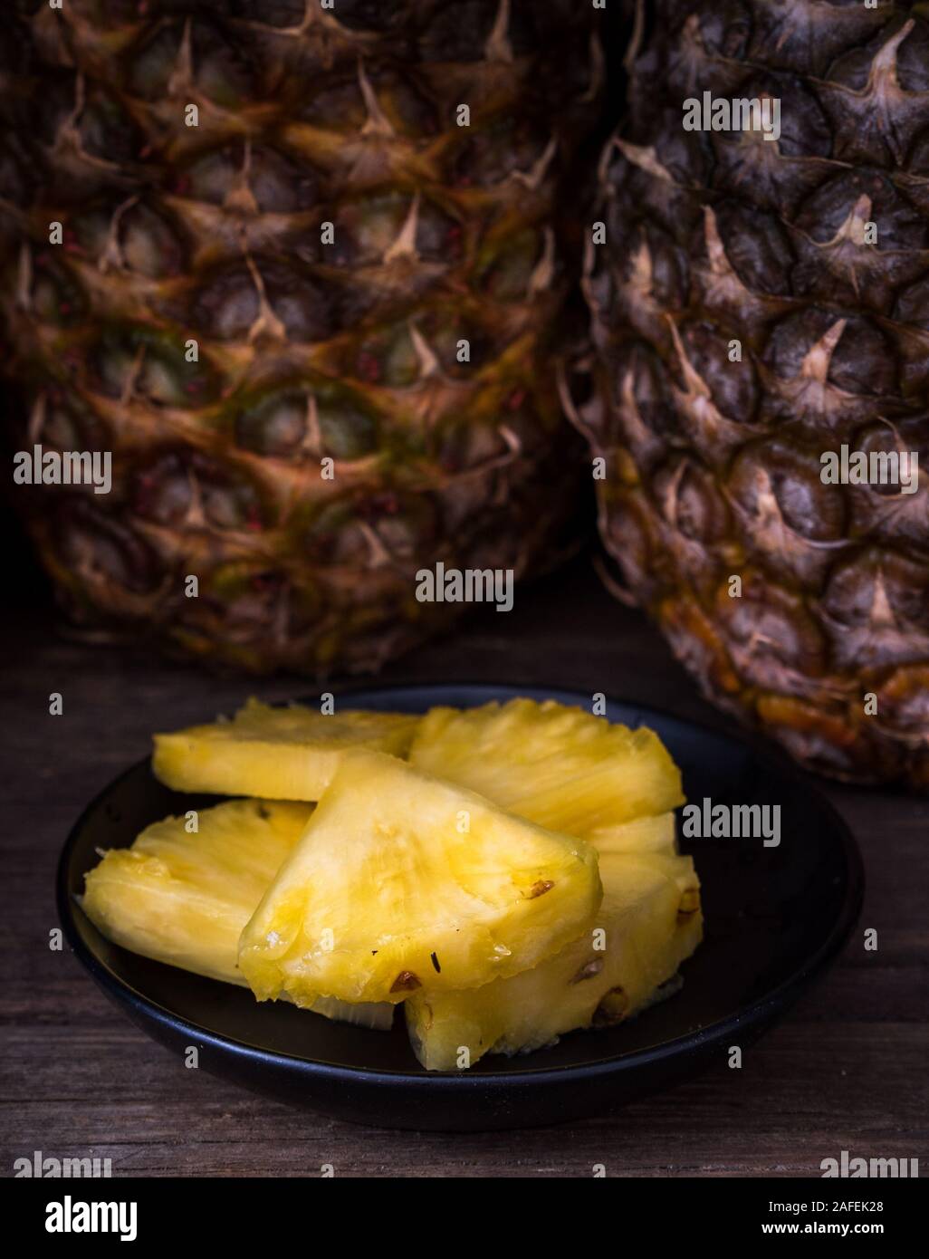Sliced pineapple on old rustic desk Black background. Stock Photo
