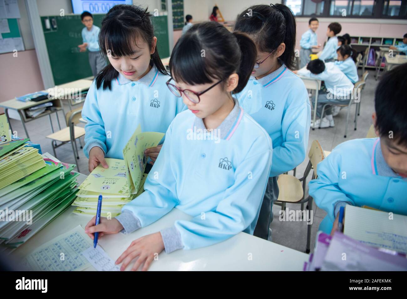 (191215) -- MACAO, Dec. 15, 2019 (Xinhua) -- Yu In Sin (1st L, front) and her schoolmates arrange the exercise books at the classroom of the Premier School Affiliated to Hou Kong Middle School in Macao, south China, Nov. 25, 2019. The 10-year-old Yu, born in Macao, is a fifth-grade student of the Premier School Affiliated to Hou Kong Middle School. Her brother also studies at the school.    In the eyes of her mother, Yu In Sin is an optimistic, sunny and lively girl with many talents. She has won many awards in Macao primary school students' storytelling, recitation, art and dance competitions Stock Photo