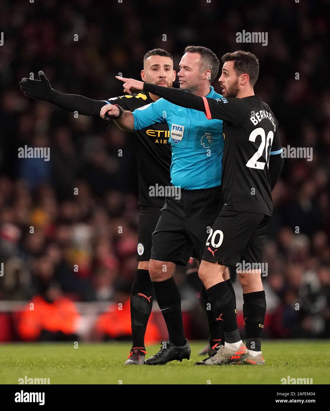 Manchester City's Nicolas Otamendi (left) and Bernardo Silva (right) speak with referee Paul Tierney during the Premier League match at The Emirates Stadium, London. Stock Photo