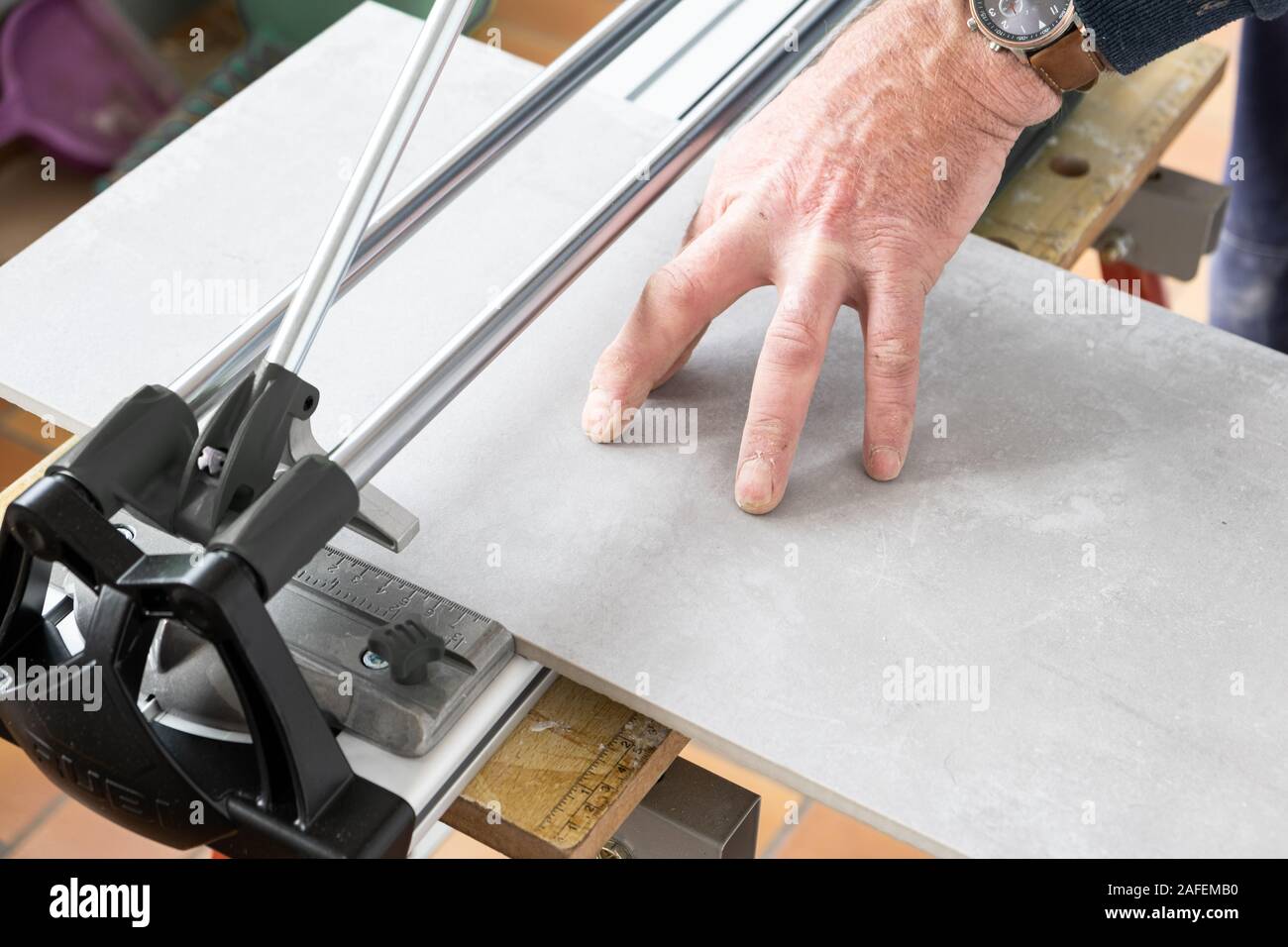 the mason cuts a ceramic tile with a tile cutter Stock Photo