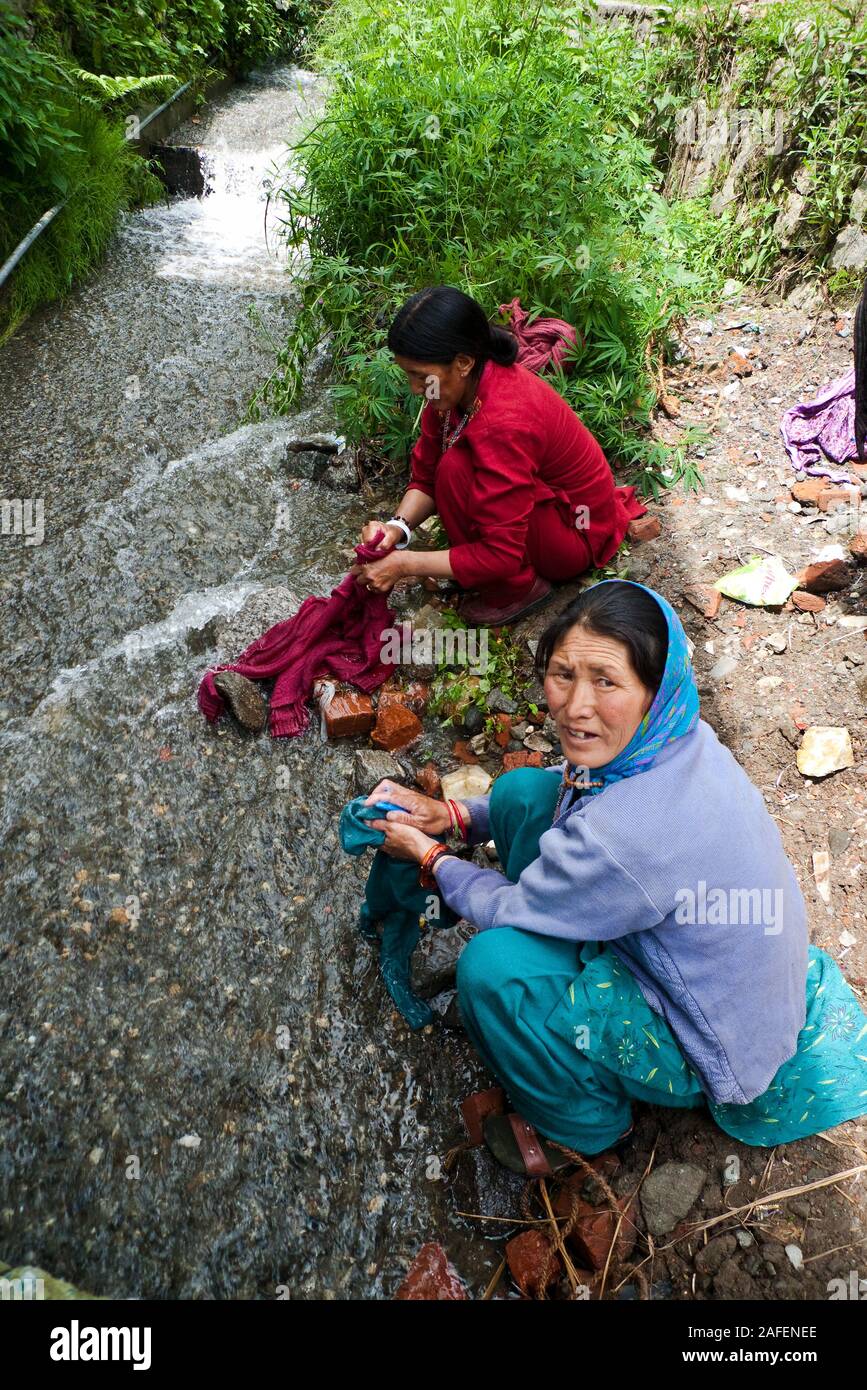 Manali, India, Himachal Pradesh: two Indian women of Tibetan descent wash clothes in a stream Stock Photo