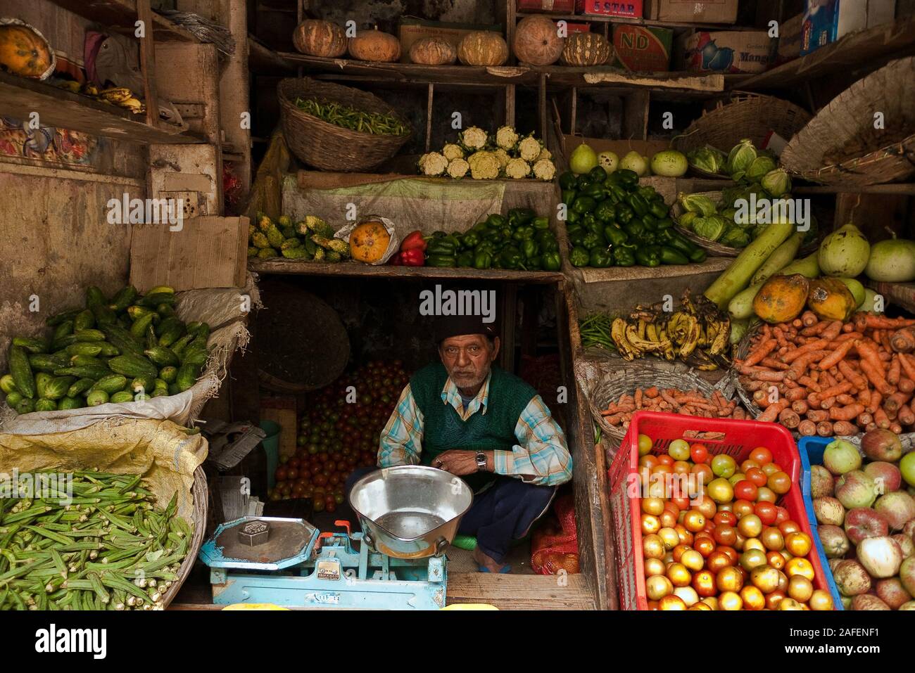 Manikaran, Himachal Pradesh, India: a greengrocer among fruit and vegetables in his shop Stock Photo