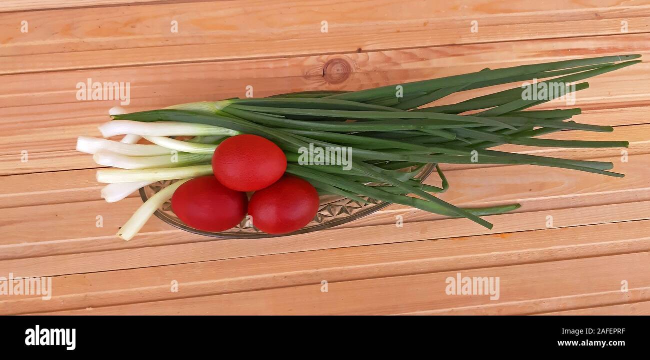 Spring onions and Easter red eggs on wooden background Stock Photo