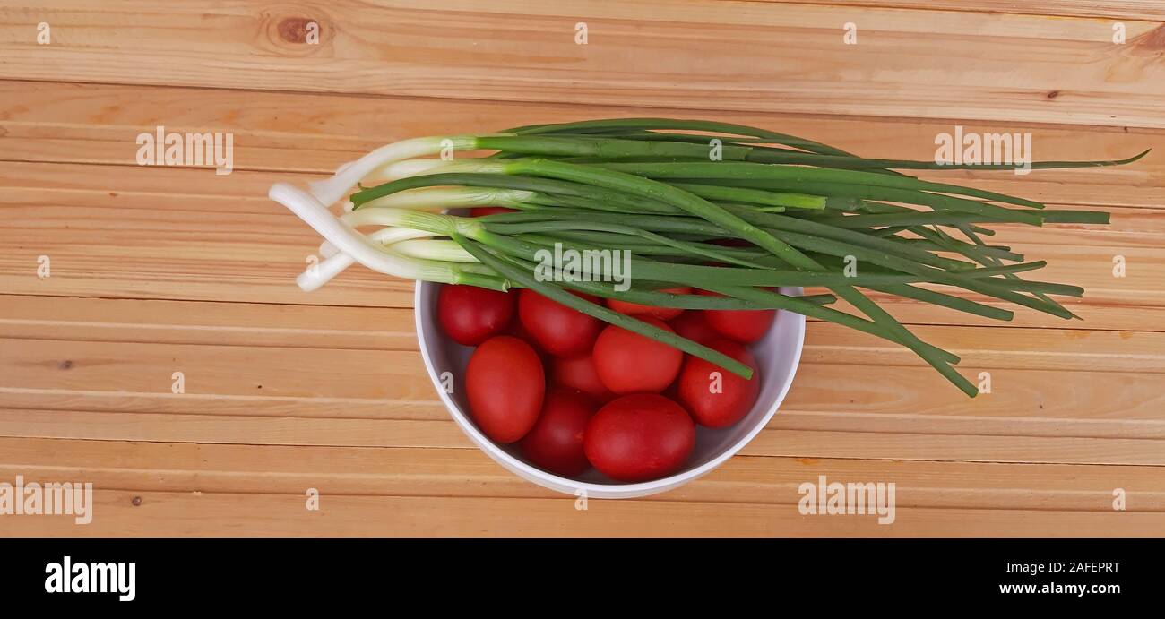 Spring onions and Easter red eggs on wooden background Stock Photo